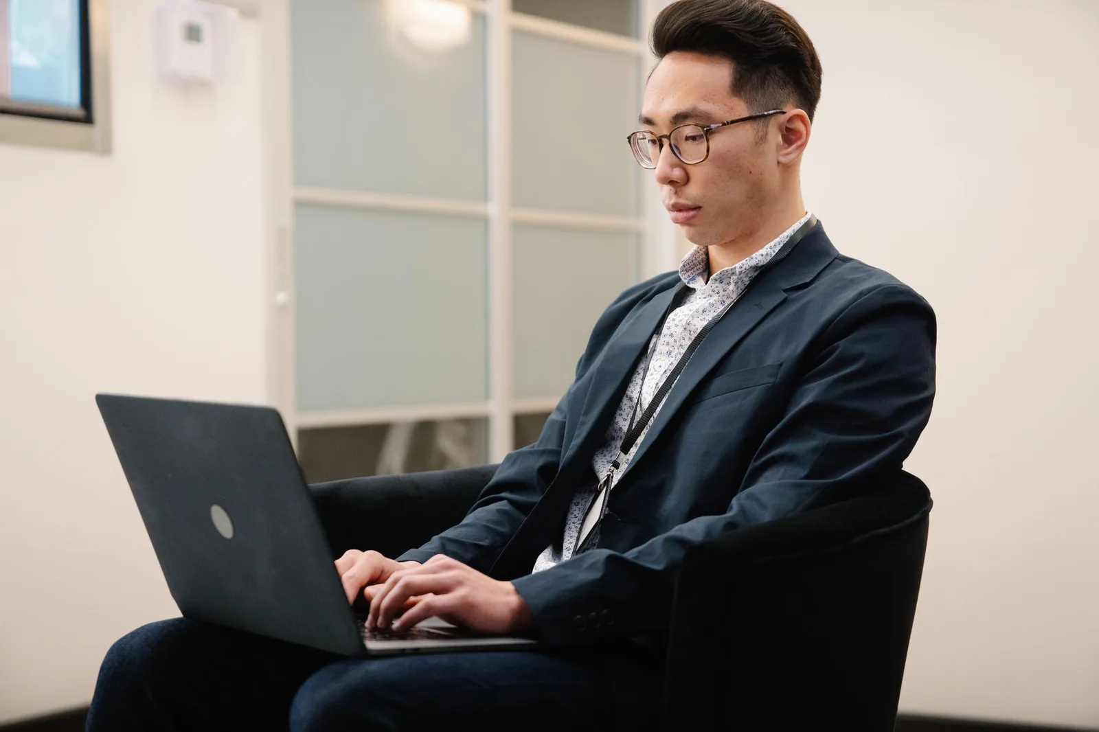 Chàng trai châu Á suy nghĩ trước màn hình laptop