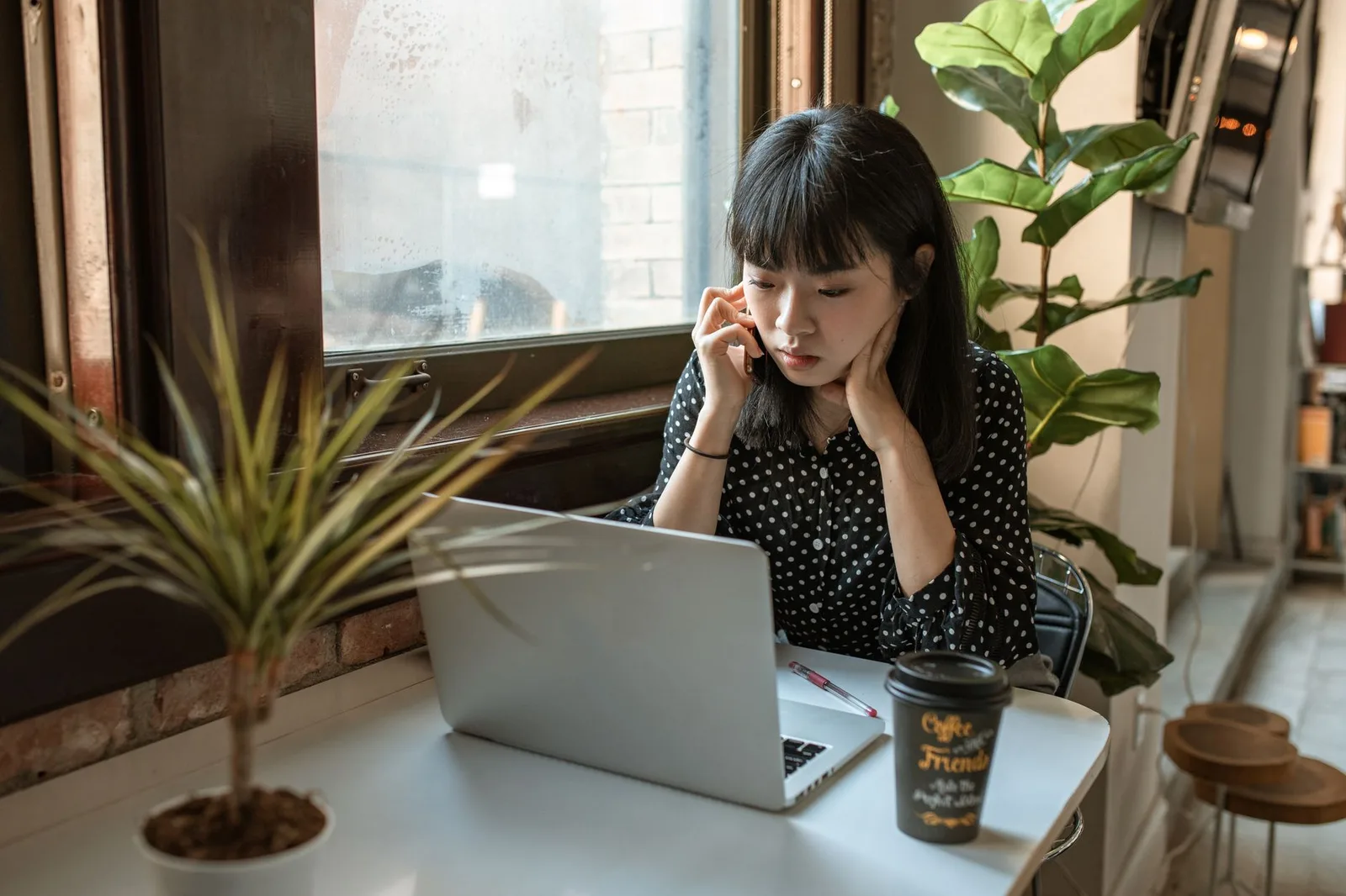 Ứng viên chỉnh sửa CV trên laptop bên tách cà phê