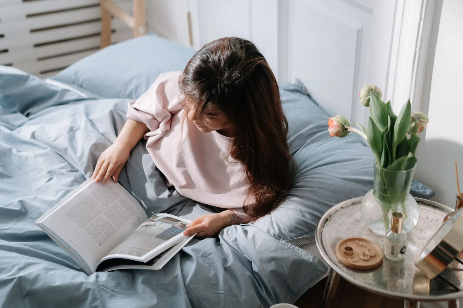 Cô gái châu Á đọc sách trong phòng ngủ ấm cúng