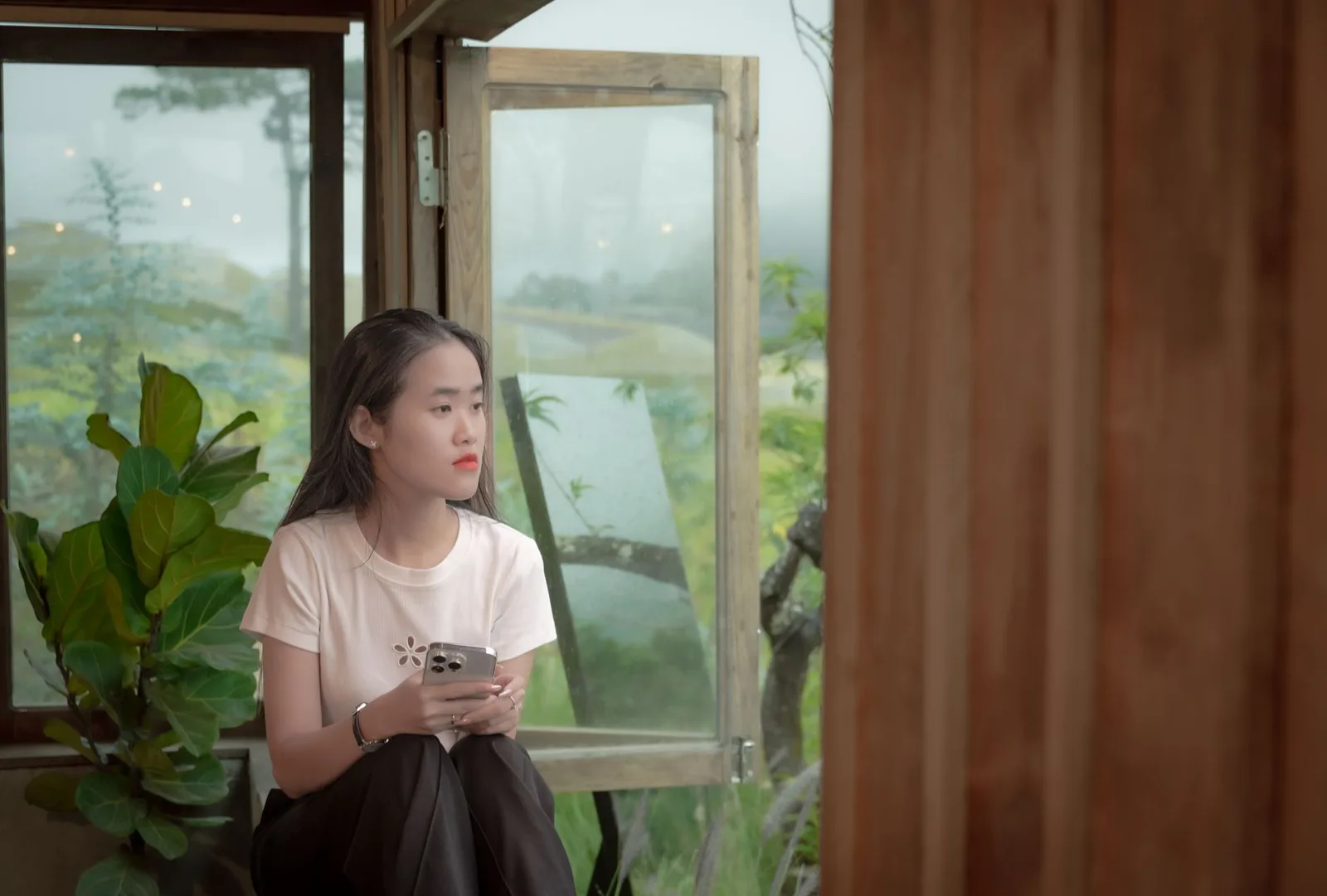Người phụ nữ châu Á ngồi bên cửa sổ, trầm tư