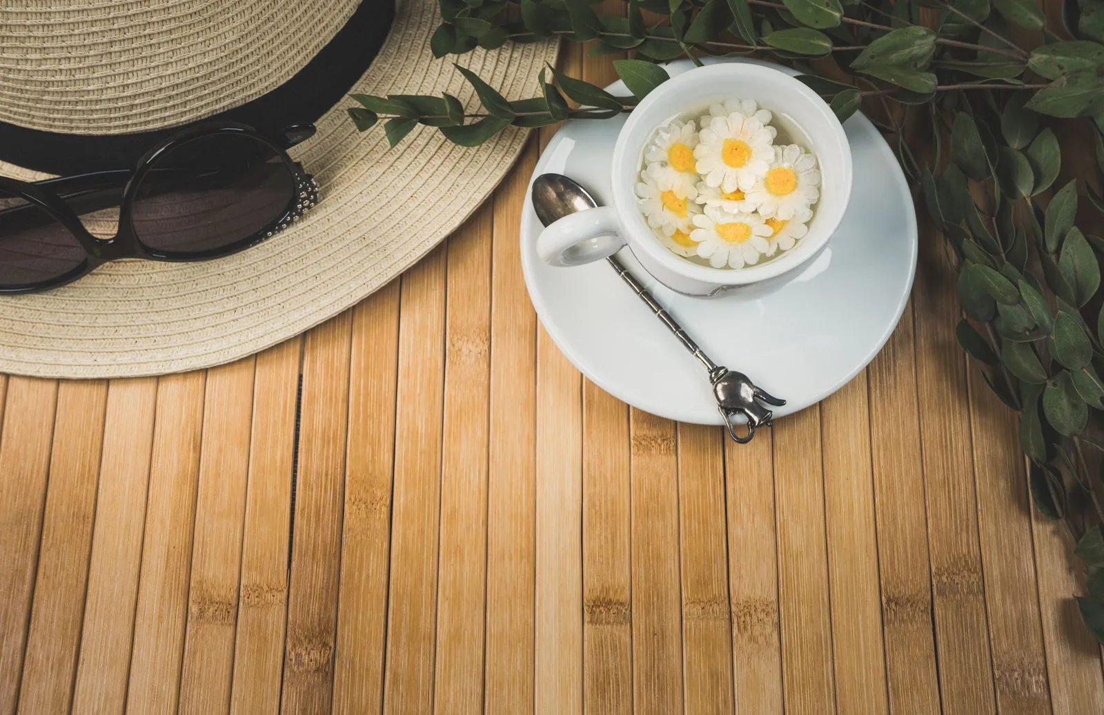 Lá trà xanh tươi và chén trà bày trên chiếu tre