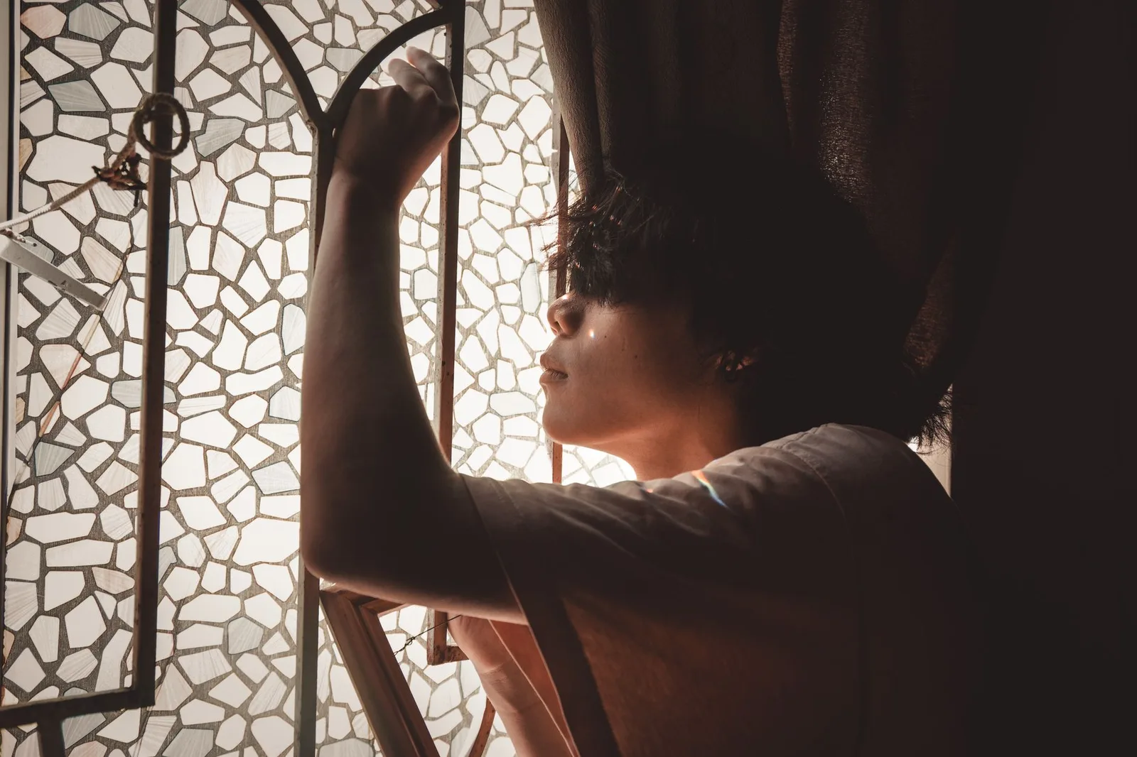 Người đàn ông châu Á ngồi một mình bên cửa sổ, trầm tư về mối quan hệ