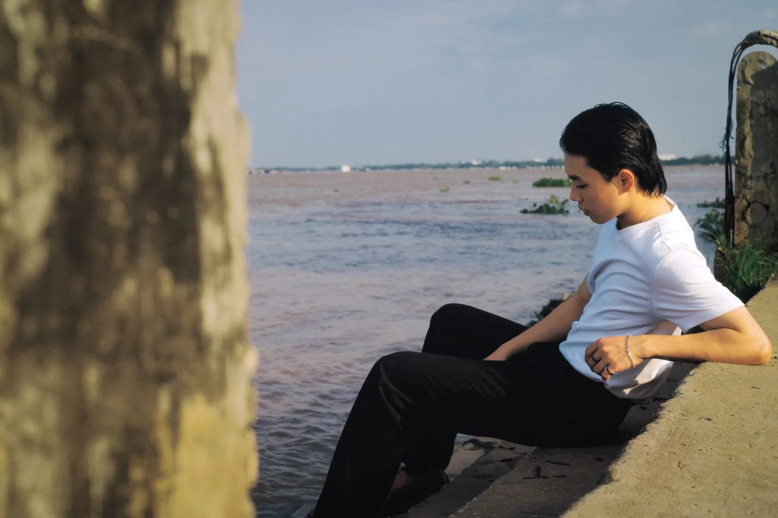 Người đàn ông châu Á ngồi một mình trong quán cà phê, trầm ngâm suy nghĩ