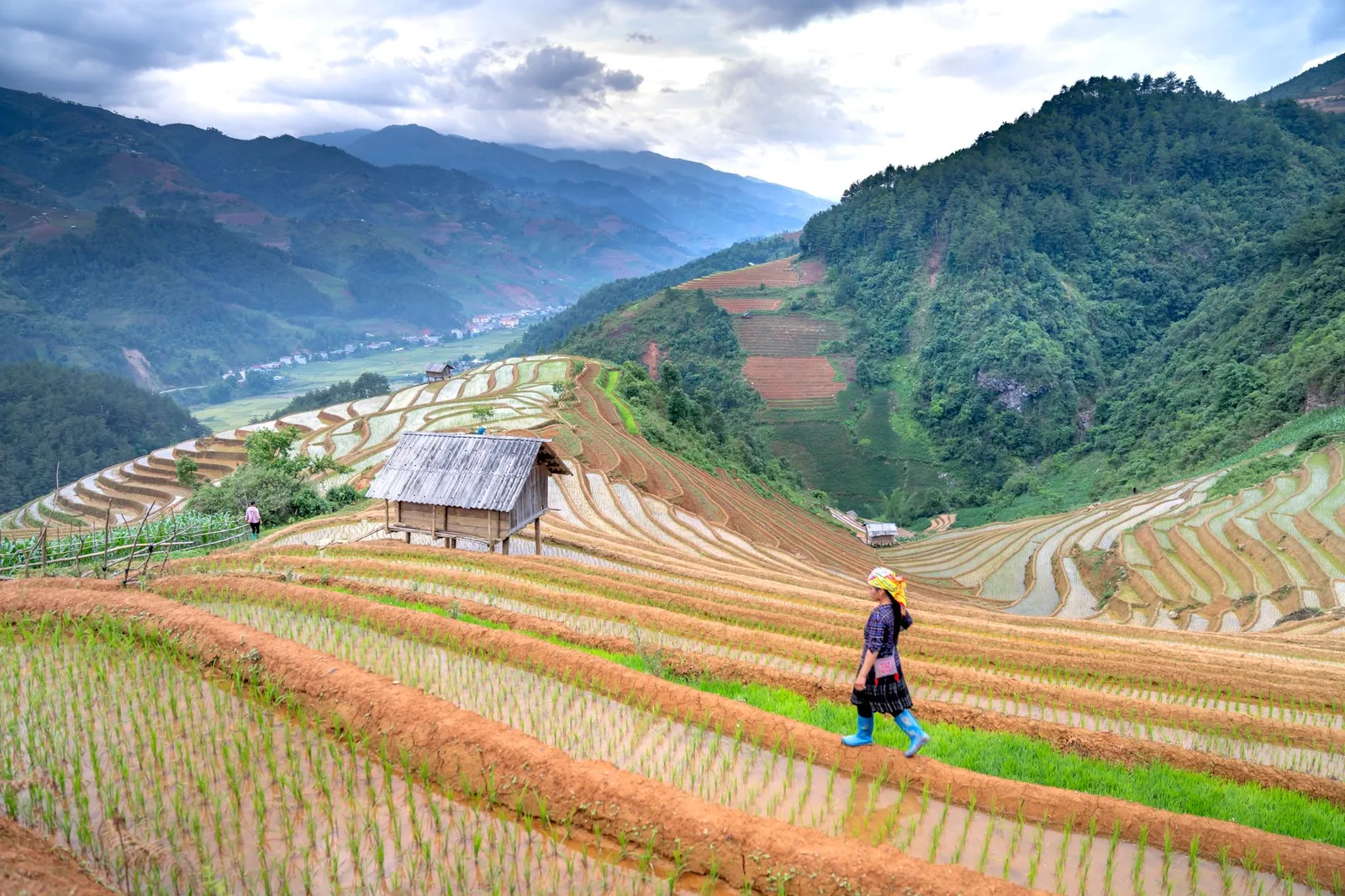 Người trekking đi bộ qua bản nhỏ giữa ruộng bậc thang