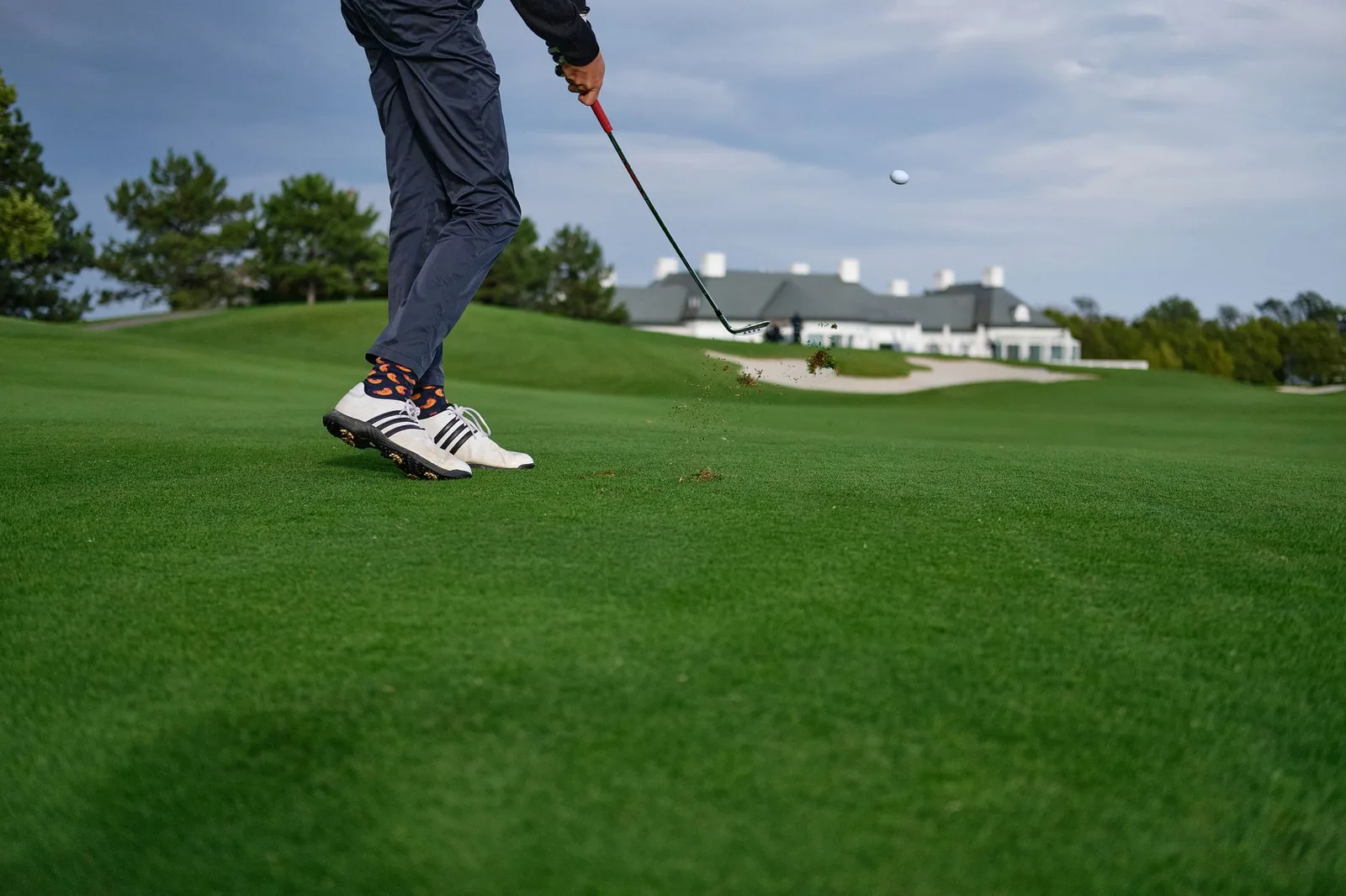 Golfer châu Á kiểm tra thông tin trên điện thoại tại câu lạc bộ