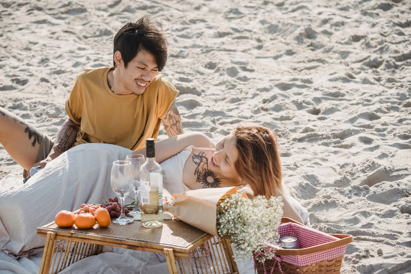 Cặp đôi châu Á picnic tiết kiệm bên biển lúc hoàng hôn
