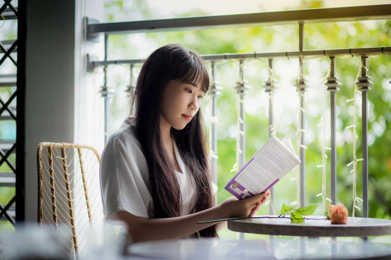 Cô gái châu Á đọc sách trên ban công homestay vào buổi sáng