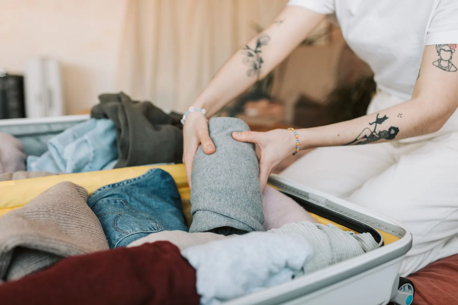 Đôi tay có móng đẹp đang sắp xếp hành lý vào vali
