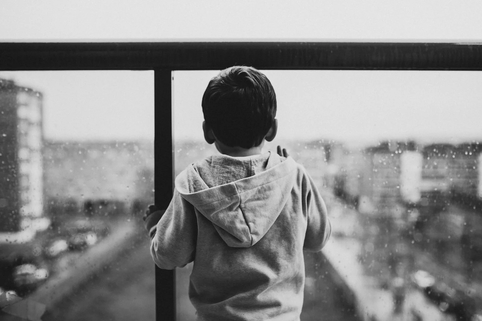 Đứa trẻ ngồi một mình bên cửa sổ, buồn bã
